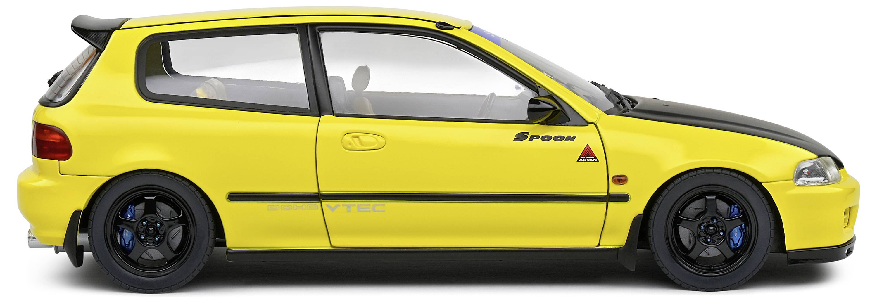 Gelber Sportwagen, Seitenansicht. Aufschrift 'Spoon' auf der Tür. Sportliches Design mit schwarzem Dach und blauen Felgen.