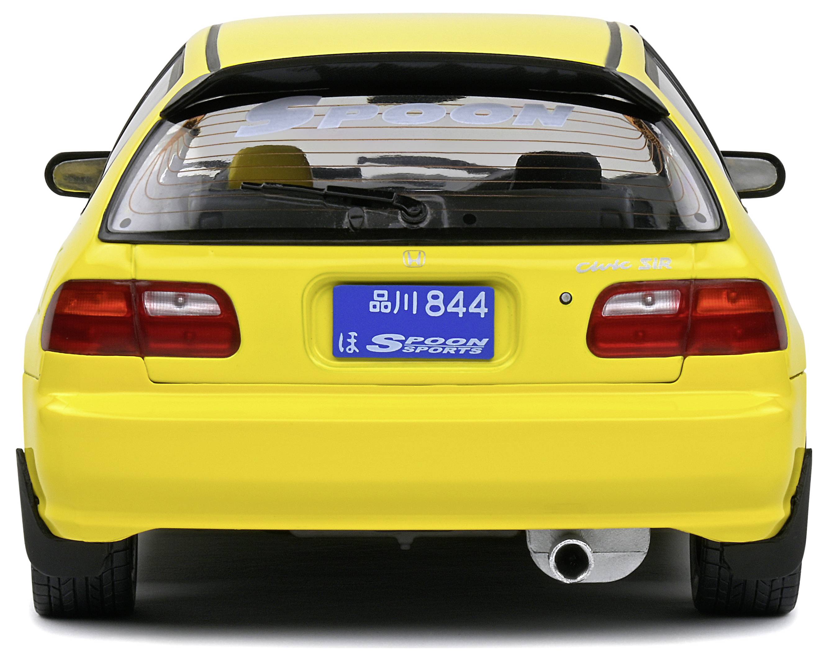 Ein gelbes Auto von hinten, mit blauer Nummernschild und Aufschrift 'Spoon Sports'.