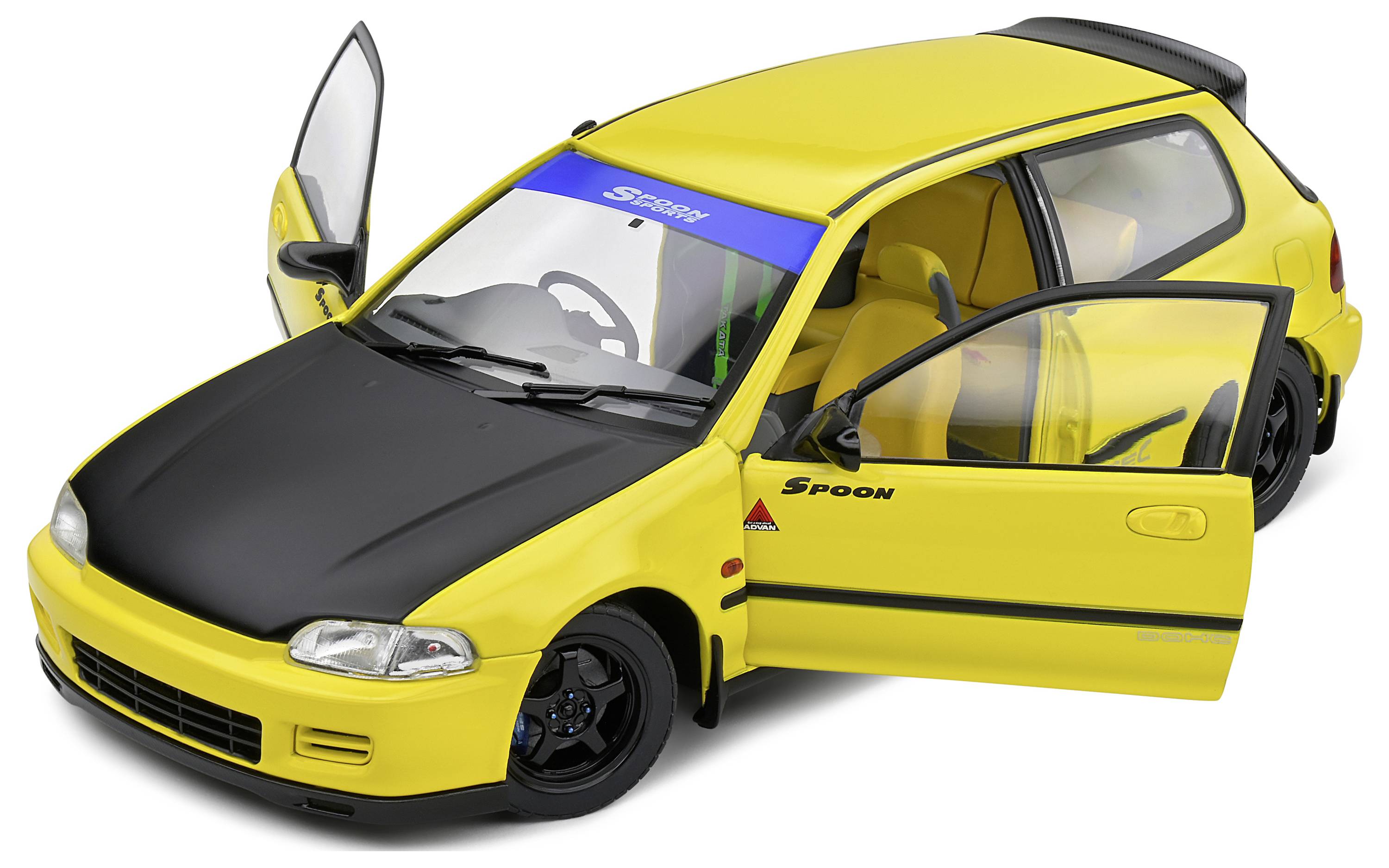 Ein gelbes Auto mit geöffneten Türen, schwarzer Motorhaube und Spoiler. Beschriftung auf der Windschutzscheibe und an der Seite.