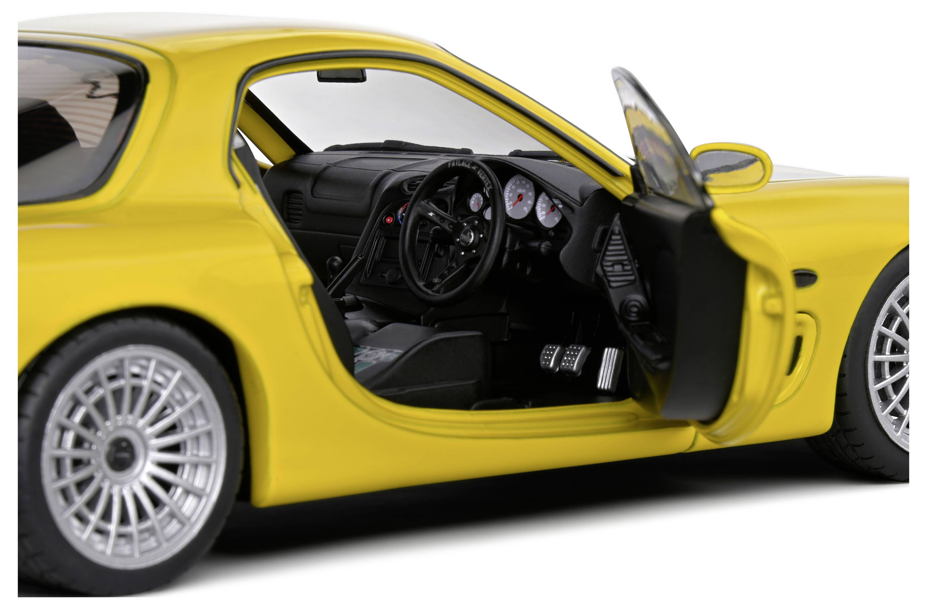 Gelbes Sportauto mit geöffneter Fahrertür, zeigt das schwarz eingerichtete Interieur und Lenkrad.