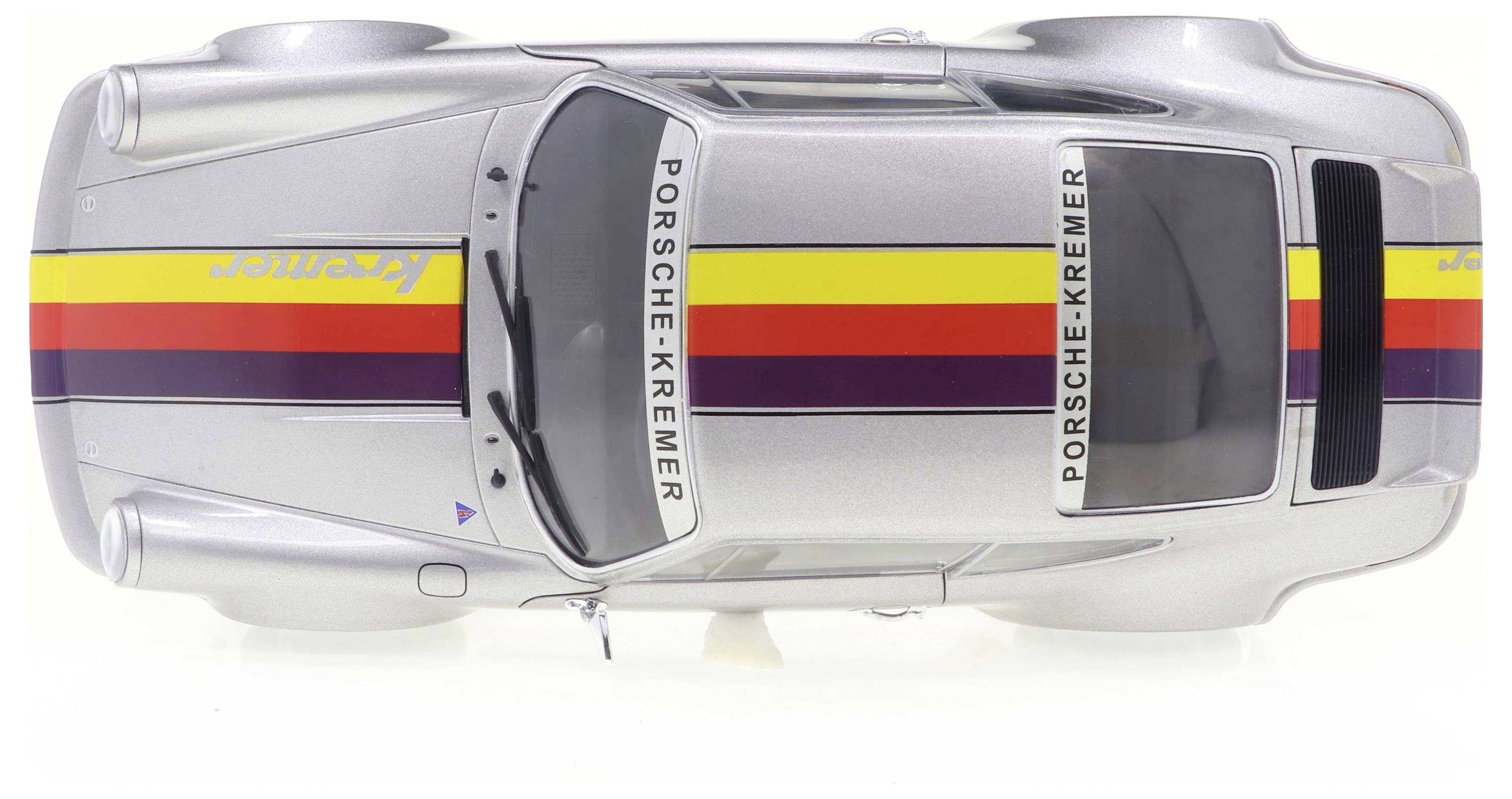 Silberner Porsche Rennwagen von oben, mit bunten Streifen in Gelb, Rot und Lila. Aufschrift 'Porsche Kremer' entlang der Seiten.