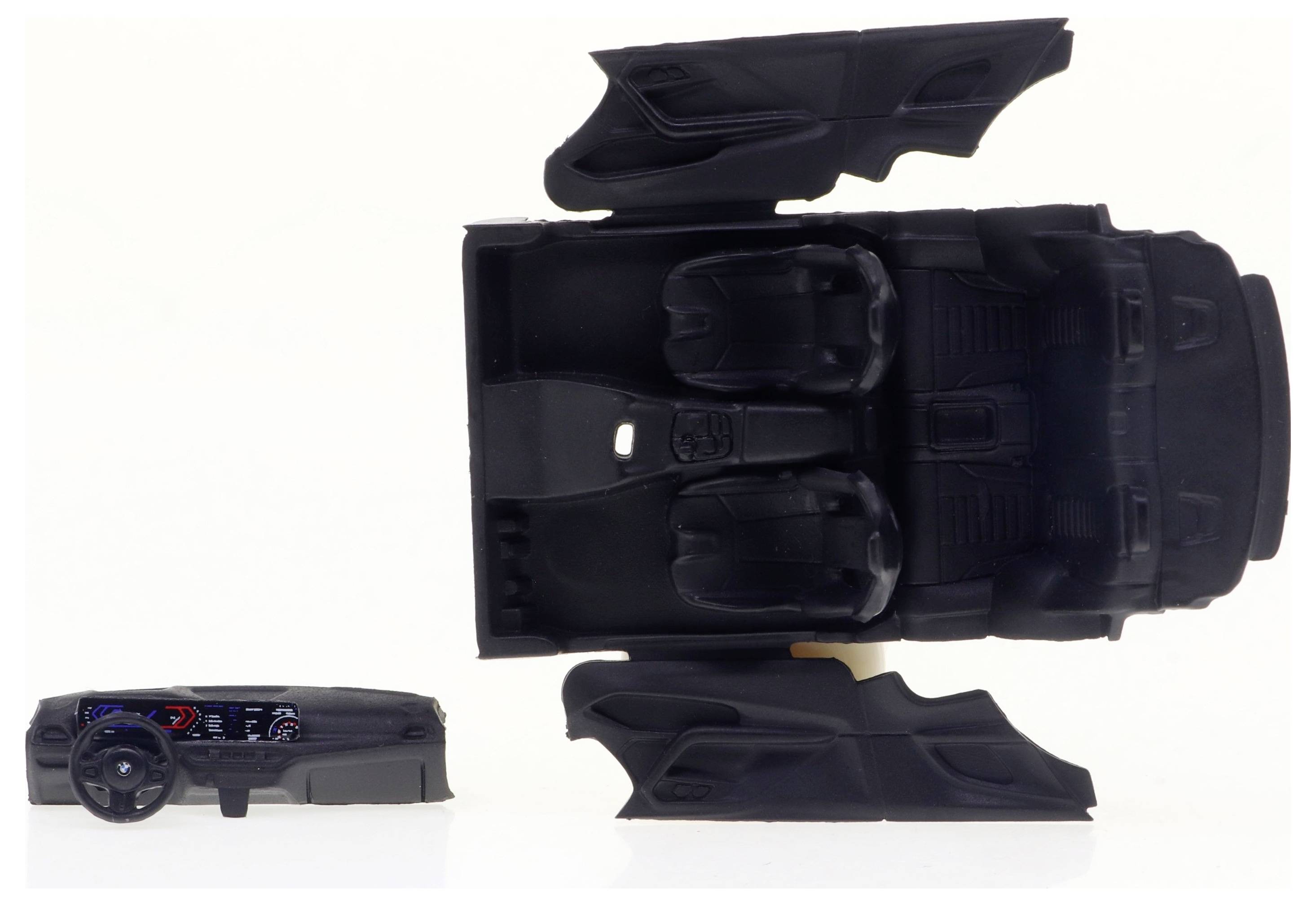 Ein Modellautoinnenraum in Schwarz mit zwei Vordersitzen, Rücksitzbank und Armaturenbrett mit Lenkrad und Instrumentenanzeige.