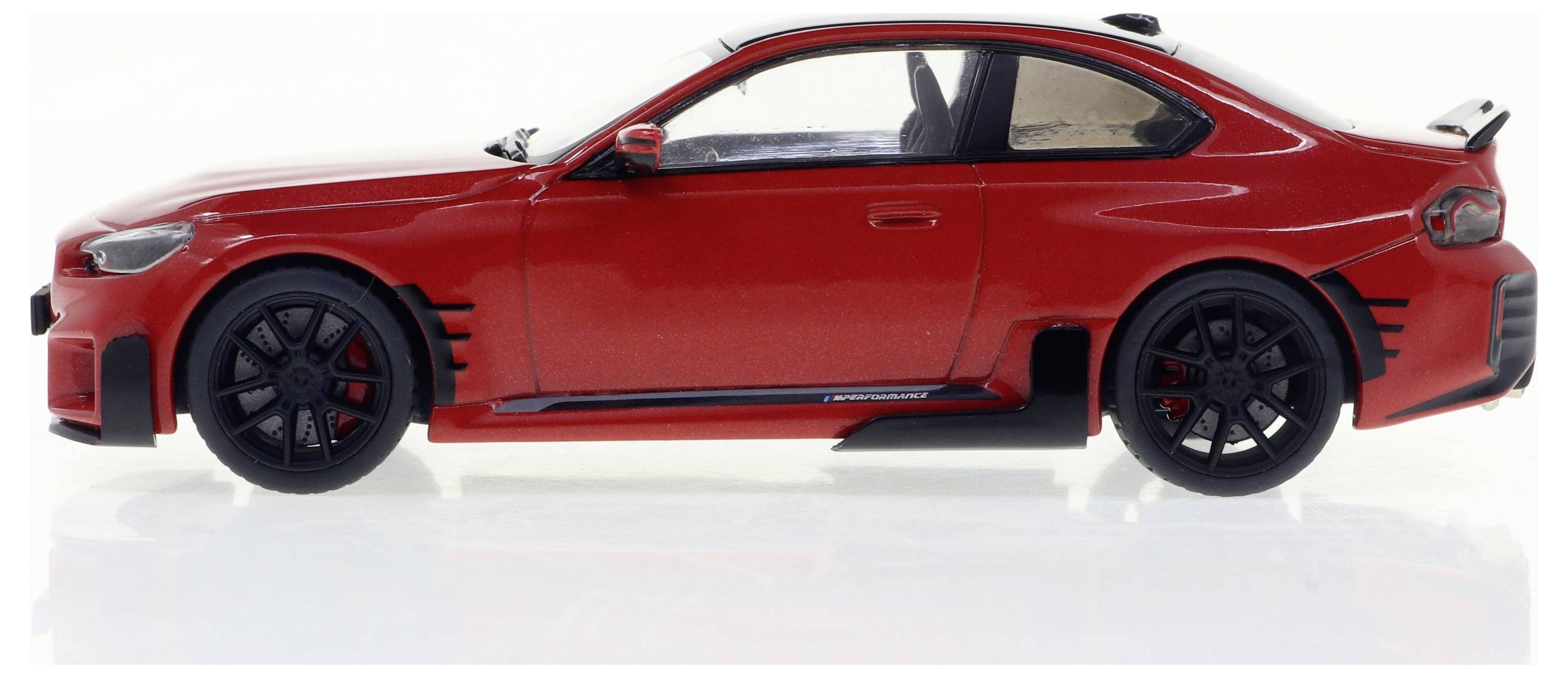 Ein rotes Modellauto in der Seitenansicht mit schwarzen Felgen und sportlichem Design auf weißem Hintergrund.