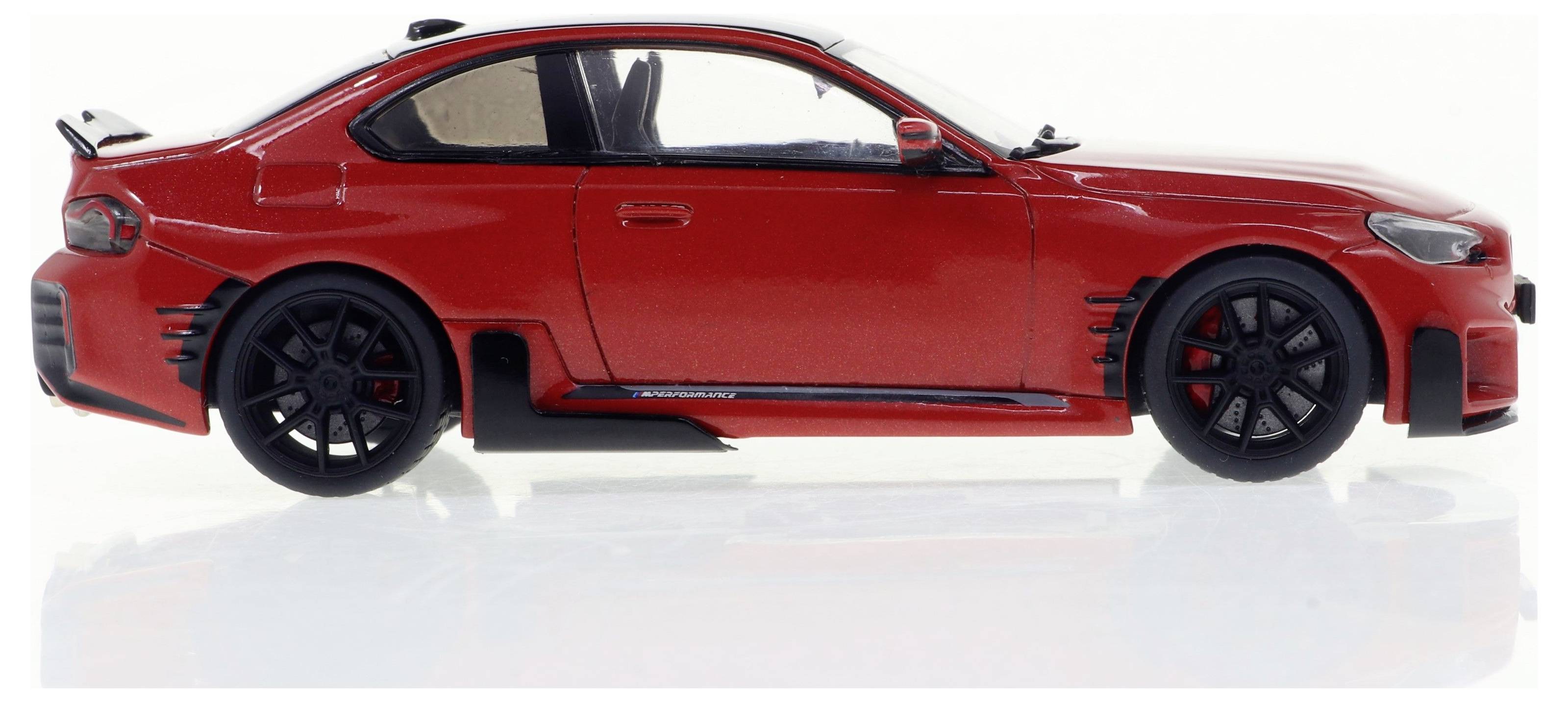 Rotes Sportwagenmodell in der Seitenansicht, mit schwarzen Felgen und aerodynamischen Details; beleuchtet vor neutralem Hintergrund.