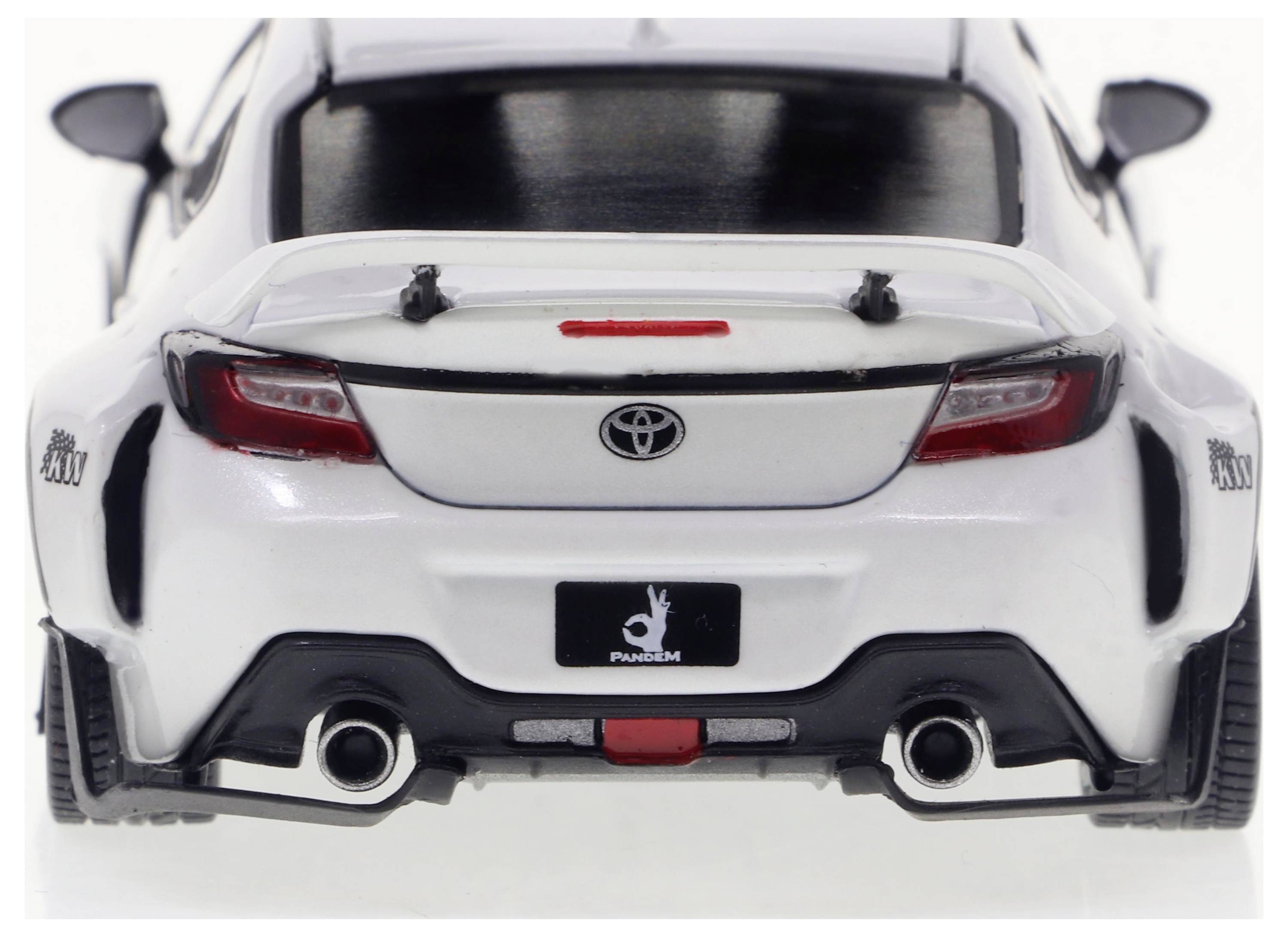 Ein weißes Auto von hinten, mit zwei Auspuffrohren und Rücklichtern. Markensymbol und Nummernschild sind sichtbar.