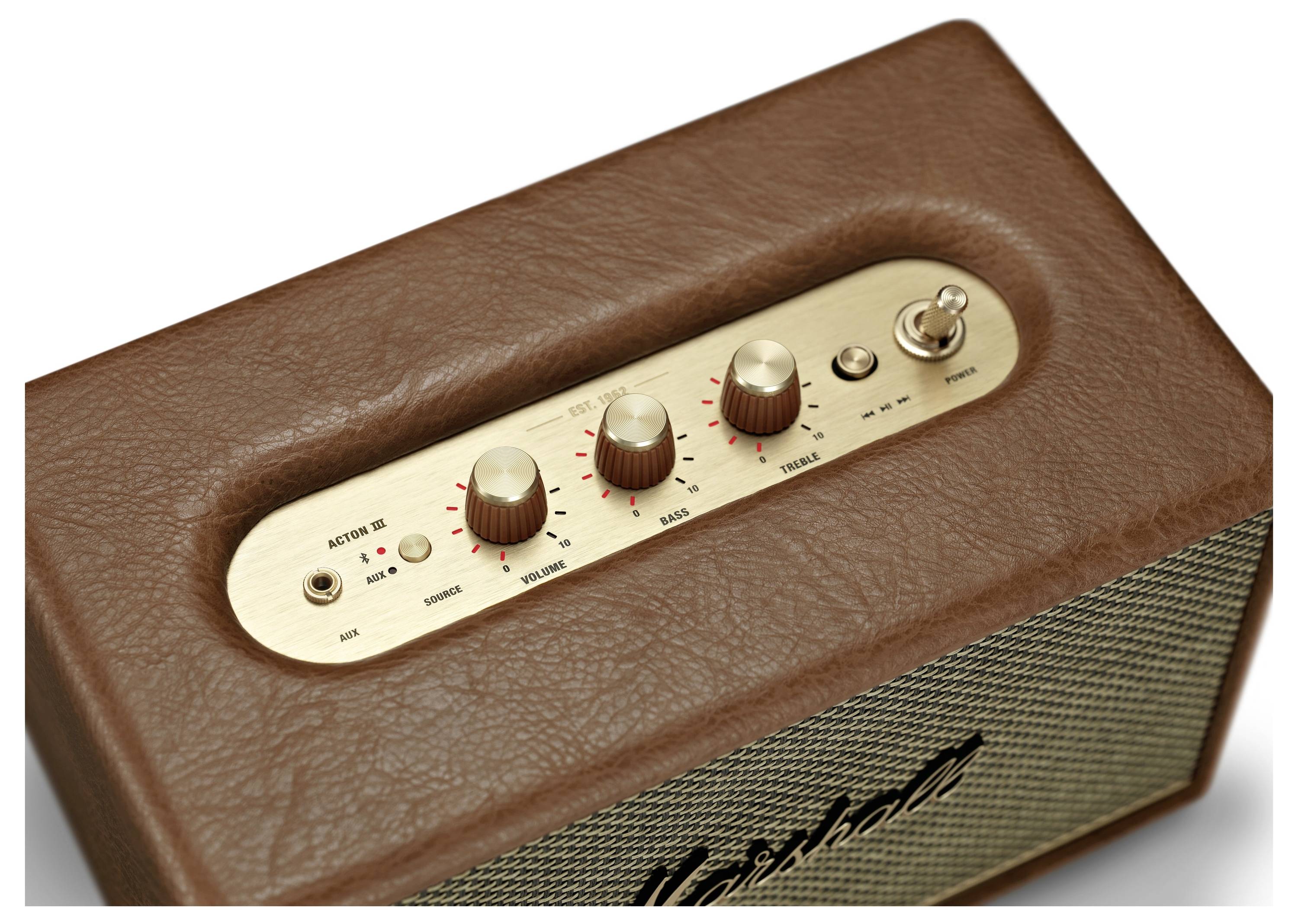 Ein brauner Lautsprecher mit einem goldenen Bedienfeld, drei Regler für Bass, Treble und Lautstärke, sowie ein Kippschalter.