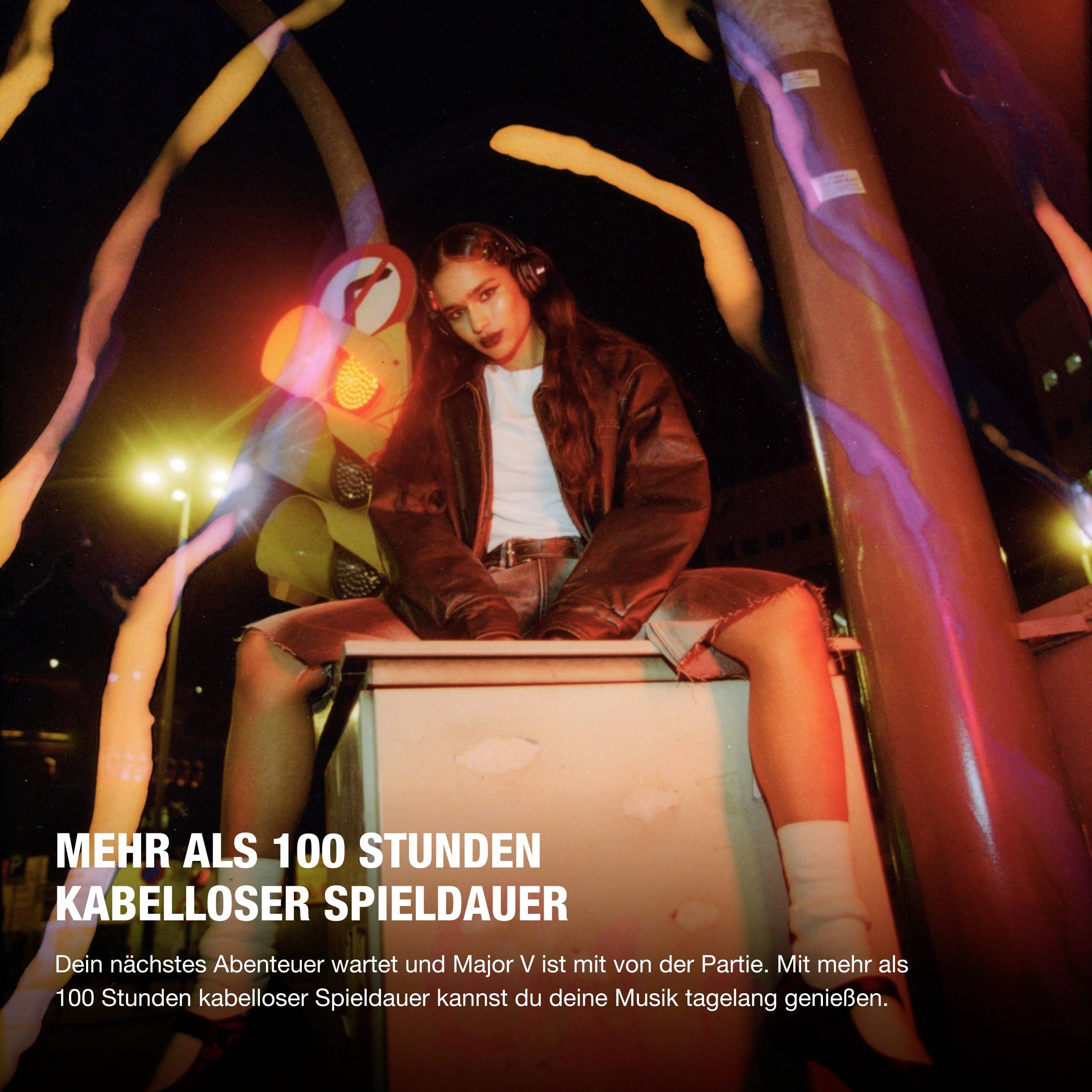 Eine Person sitzt nachts auf einem Stadtgeländer. Der Text lautet: 'Mehr als 100 Stunden kabelloser Spieldauer.'