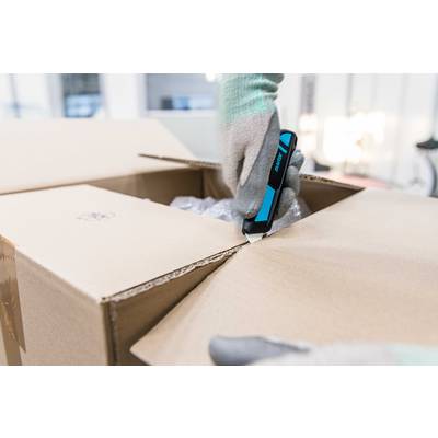 Eine Person schneidet mit einem Sicherheitscutter einen Karton auf. Sie trägt schützende Handschuhe und das Umfeld wirkt industriell.