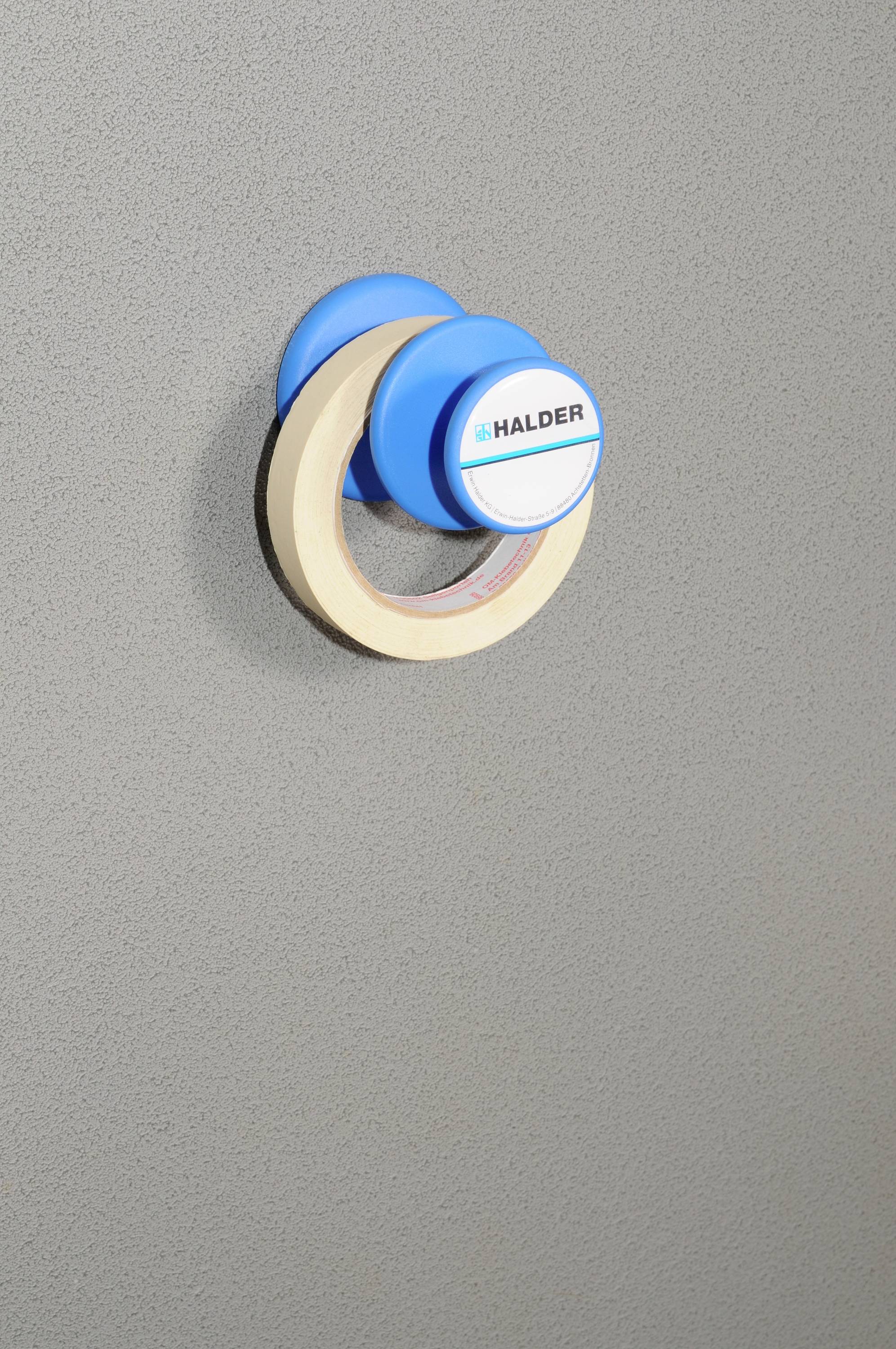 Ein Haltemagnet mit einer blauen Halterung ist an einer grauen Oberfläche befestigt. Auf der Halterung steht 'HALDER'.