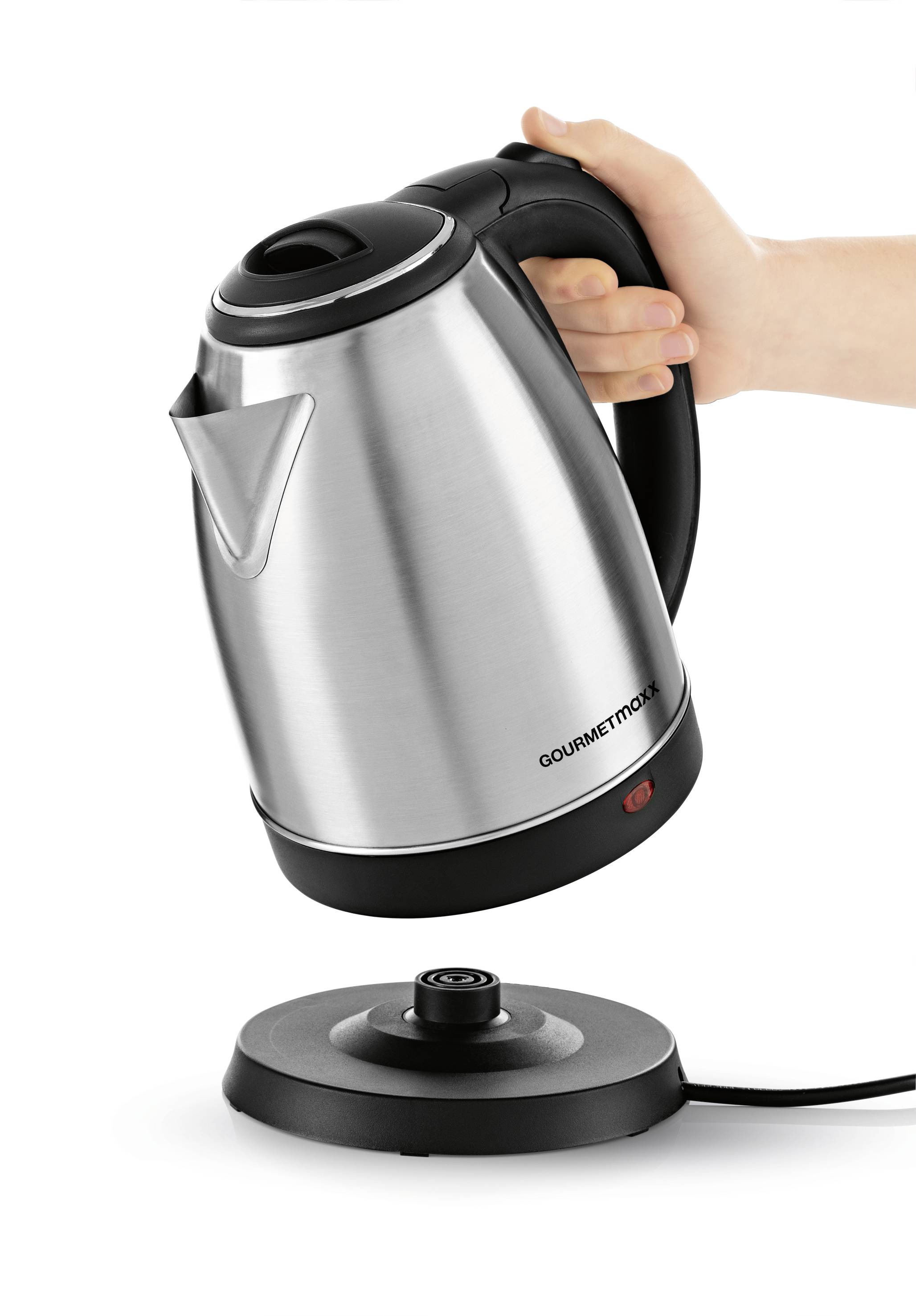 Eine Hand hält einen silbernen Wasserkocher über seine runde Basis, bereit zum Platzieren. Der Kocher hat einen schwarzen Griff.