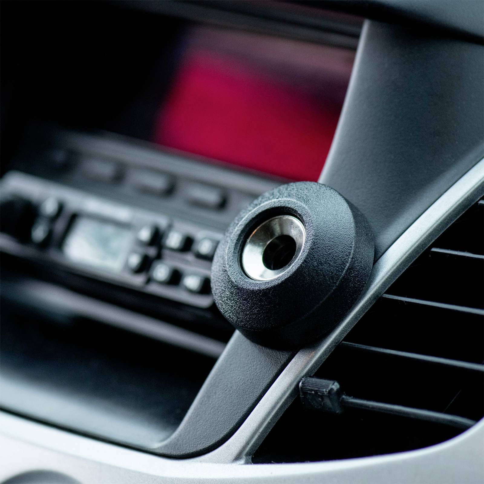 Ein Autoradio mit einem umgebauten Knauf für ein Mobilgerät oder Zubehör, eingebaut im Armaturenbrett eines Fahrzeugs.