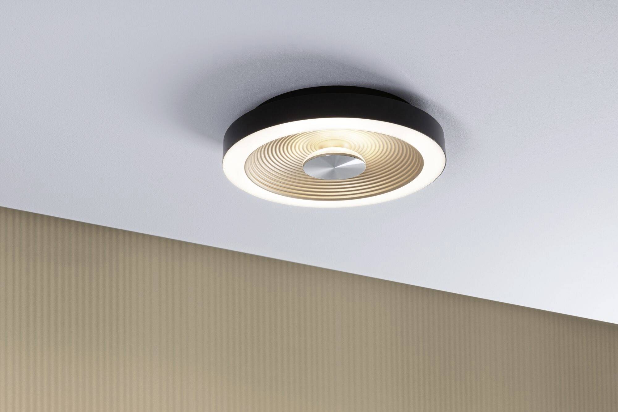 Moderne Deckenleuchte mit kreisförmigem Design und wellenförmigem Muster an der Decke eines Wohnzimmers.