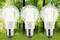 Drei Energiesparlampen vor unscharfem Waldhintergrund. Sie symbolisieren umweltfreundliche Beleuchtung und Nachhaltigkeit.