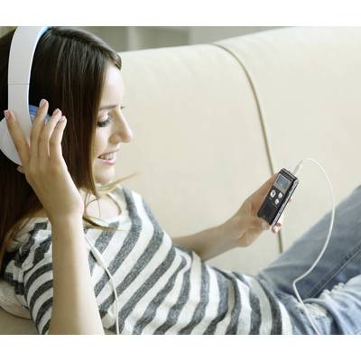 Eine Frau liegt entspannt auf einem Sofa, hört Musik mit Kopfhörern und hält ein tragbares Audiogerät in der Hand.