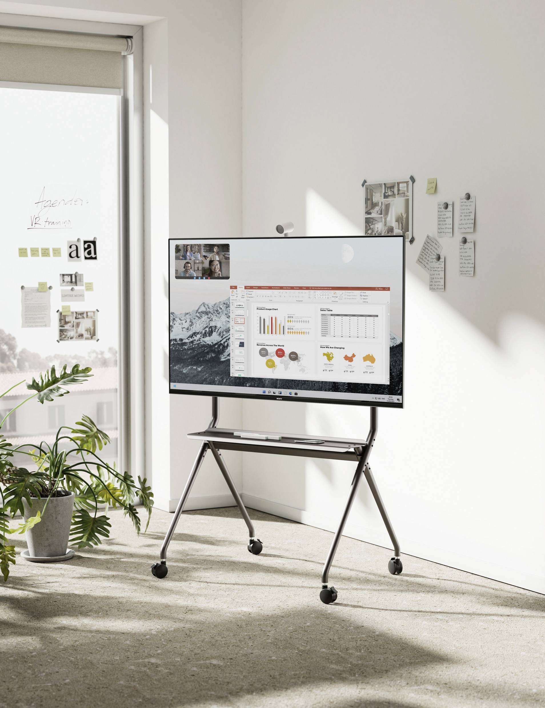 Moderner Besprechungsraum mit digitalem Whiteboard, das eine Geschäftspräsentation mit Diagrammen zeigt. Fenster im Hintergrund mit Pflanzen.