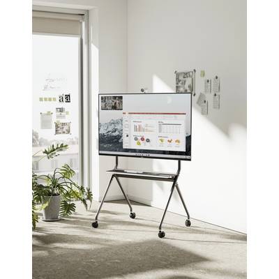 Moderner Besprechungsraum mit digitalem Whiteboard, das eine Geschäftspräsentation mit Diagrammen zeigt. Fenster im Hintergrund mit Pflanzen.