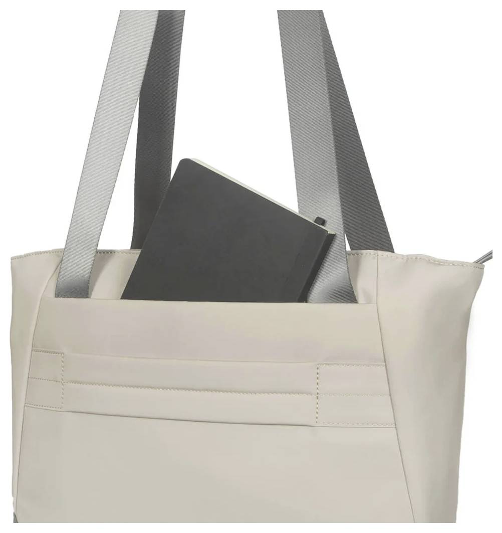 Eine beigefarbene Tasche mit grauen Trägern, in der ein schwarzes Notizbuch steckt.