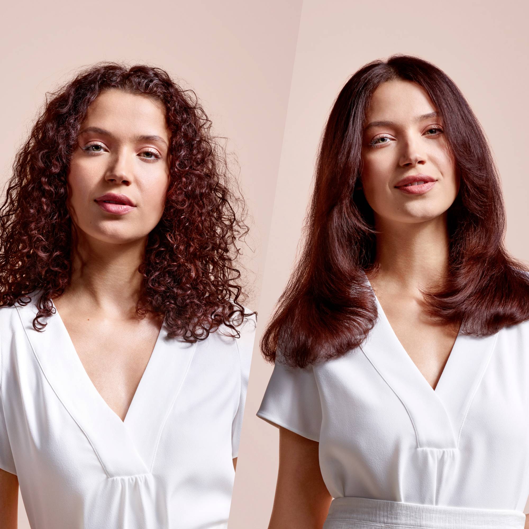 Zwei Frauen mit hellen Oberteilen stehen nebeneinander vor neutralem Hintergrund. Eine hat lockiges Haar, die andere glattes Haar.