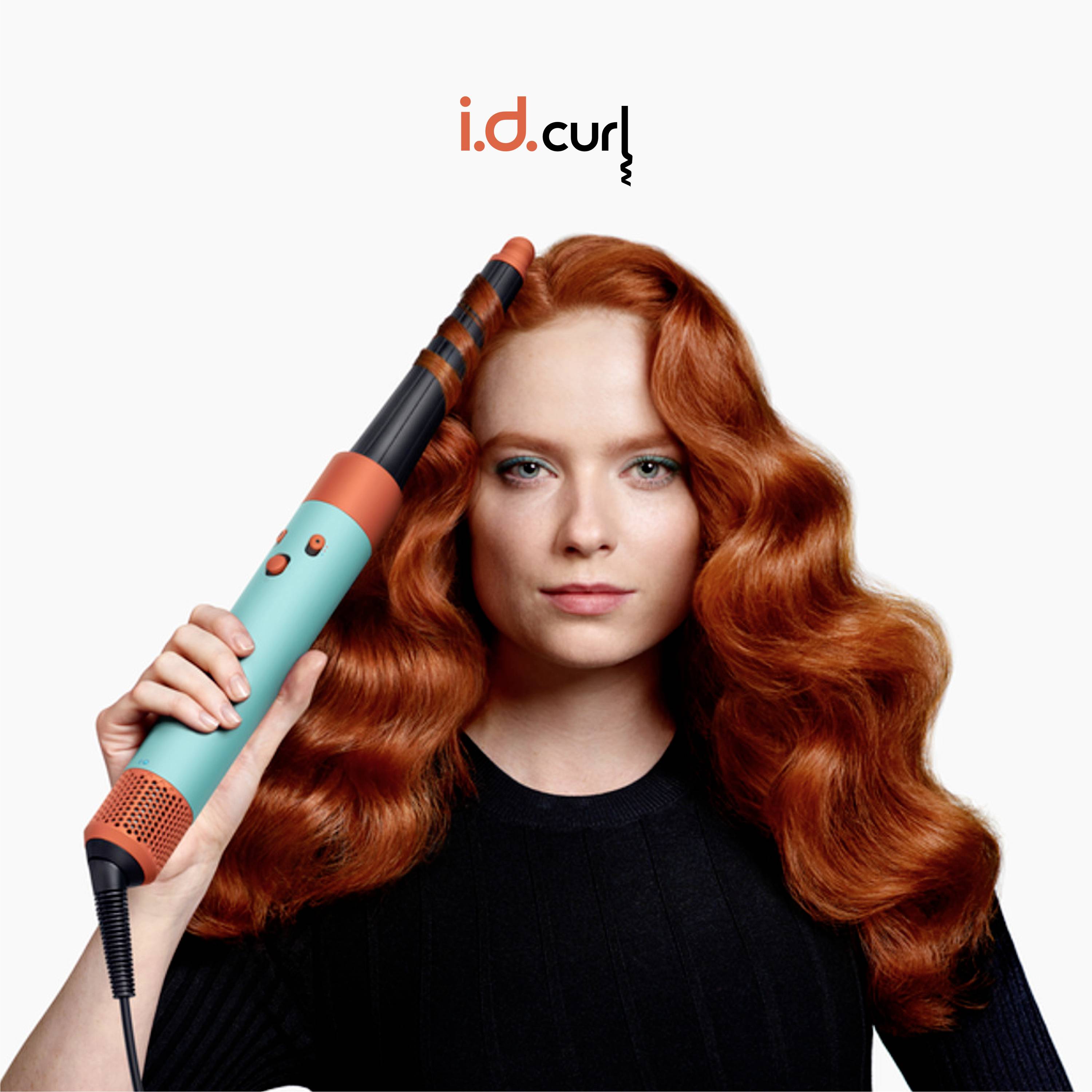 Frau mit langen, roten Locken hält einen blauen Lockenstab.