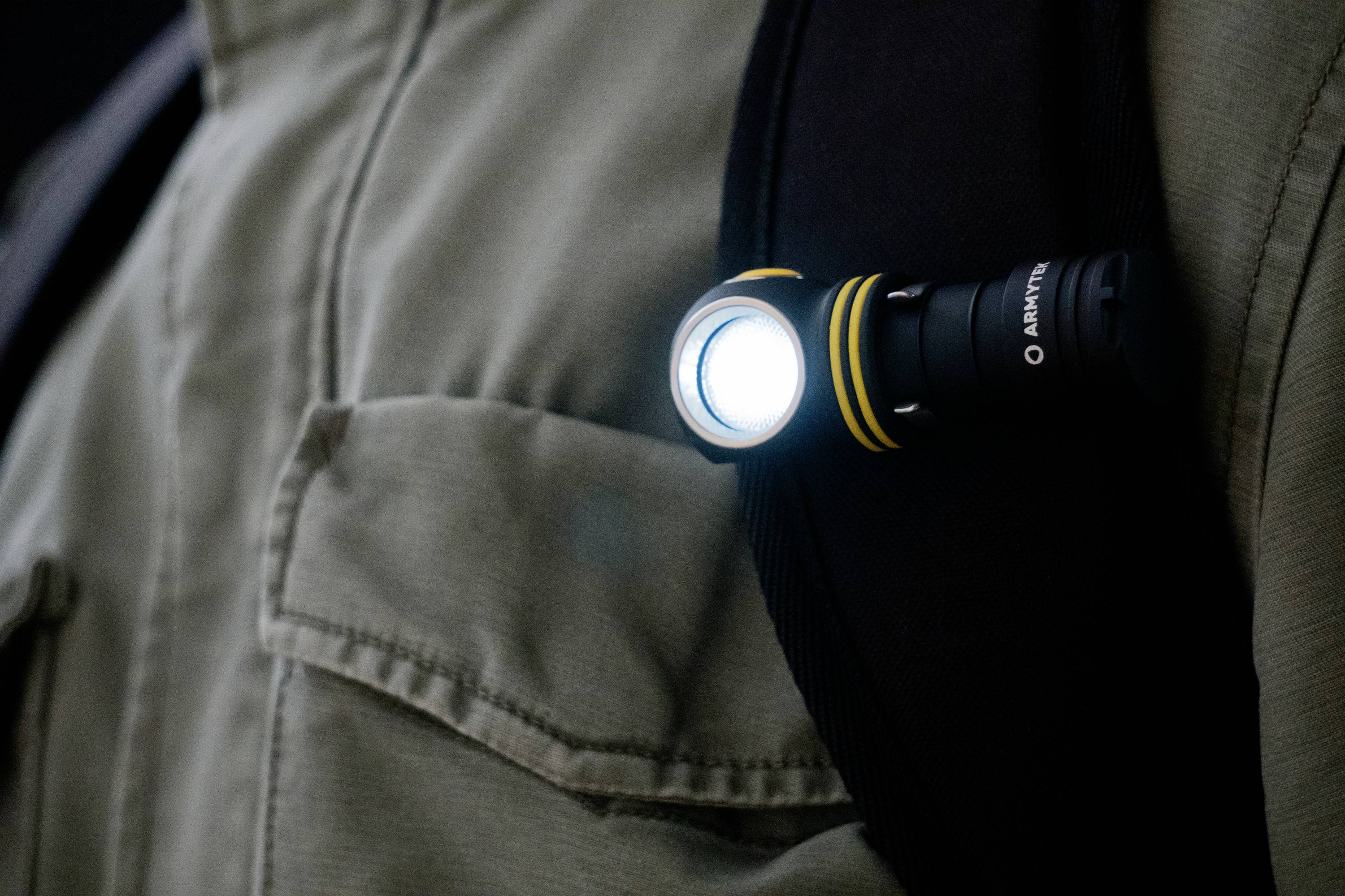 Eine leuchtende Taschenlampe ist an einem Träger oder Riemen befestigt. Sie leuchtet hell und scheint an einem Kleidungsstück angebracht zu sein.