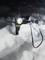 Taschenlampe im Schnee; leuchtet hell in dunkler Umgebung, von Kabel umgeben.