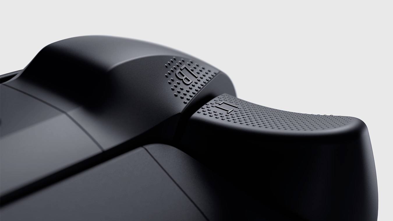 Nahaufnahme eines schwarzen Game-Controller-Triggers mit strukturiertem Griff und sichtbaren 'R1'-Markierungen, vor grauem Hintergrund.