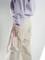 Person hält einen rosa Hand-Dampfer in der rechten Hand, trägt eine lila Sweatshirt und beige Hosen.