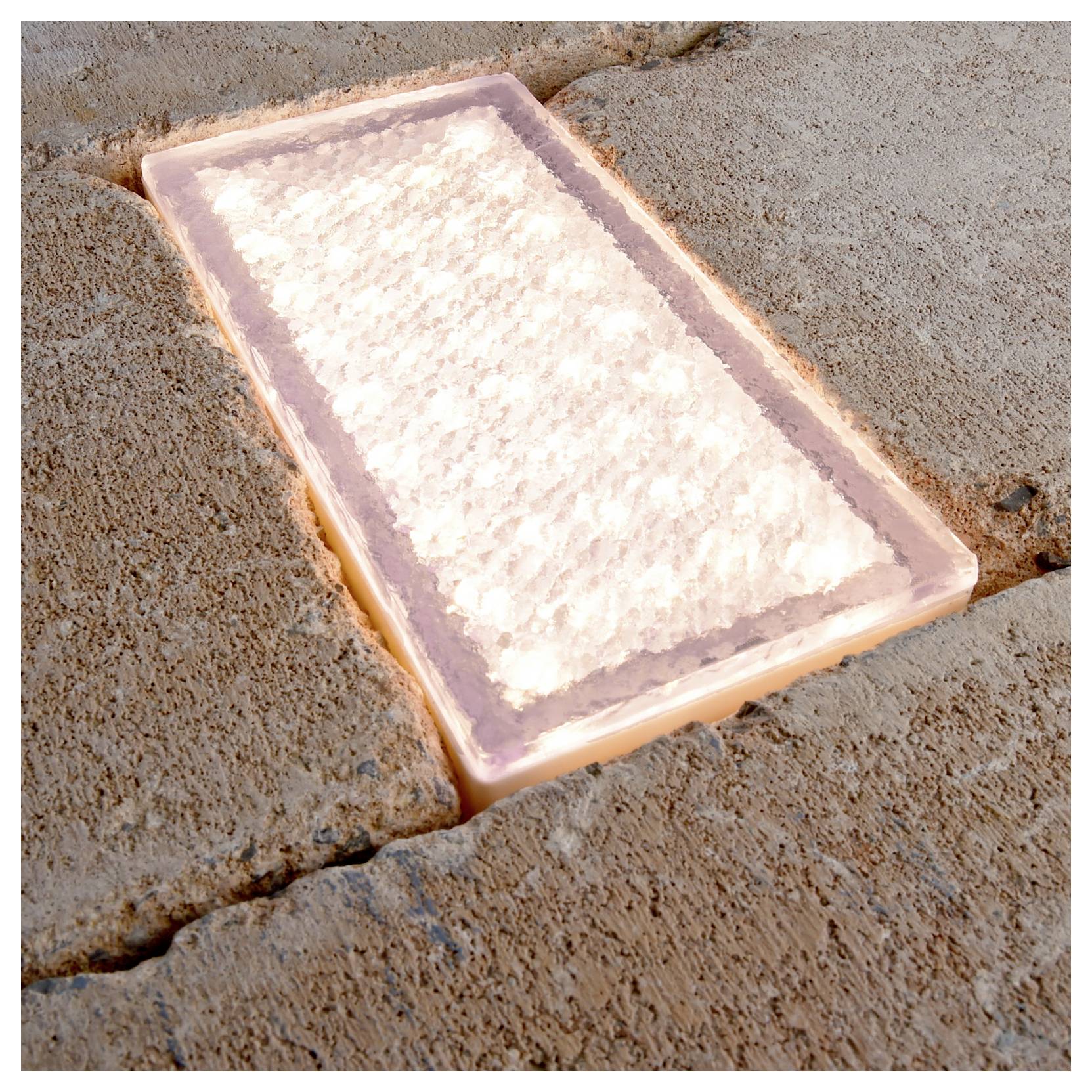 Ein Block aus rosa Himalaya-Salz, eingelassen in eine Pflasteroberfläche aus Stein.