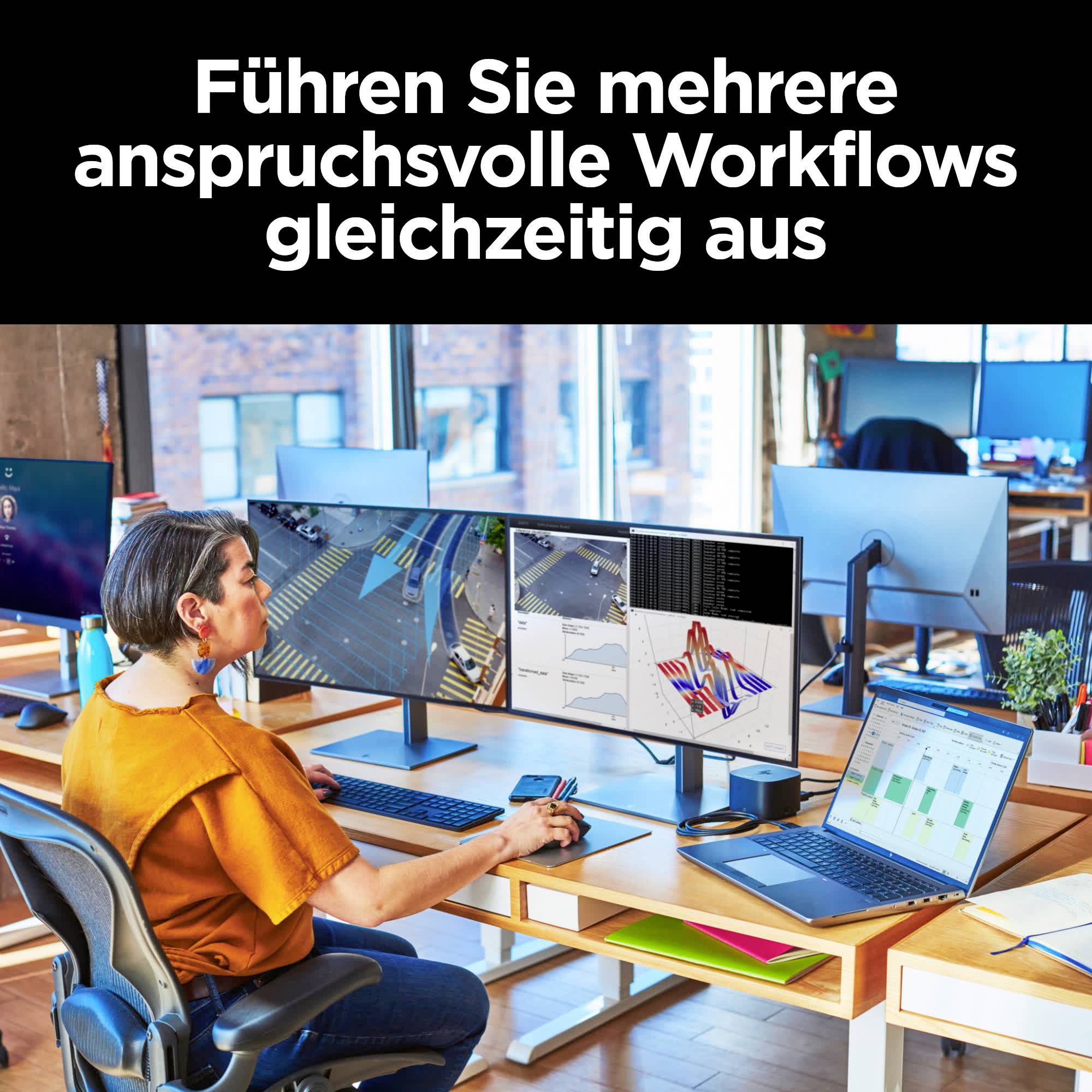 Person sitzt an einem Schreibtisch mit mehreren Computermonitoren, auf denen komplexe Arbeitsprozesse gleichzeitig ausgeführt werden.