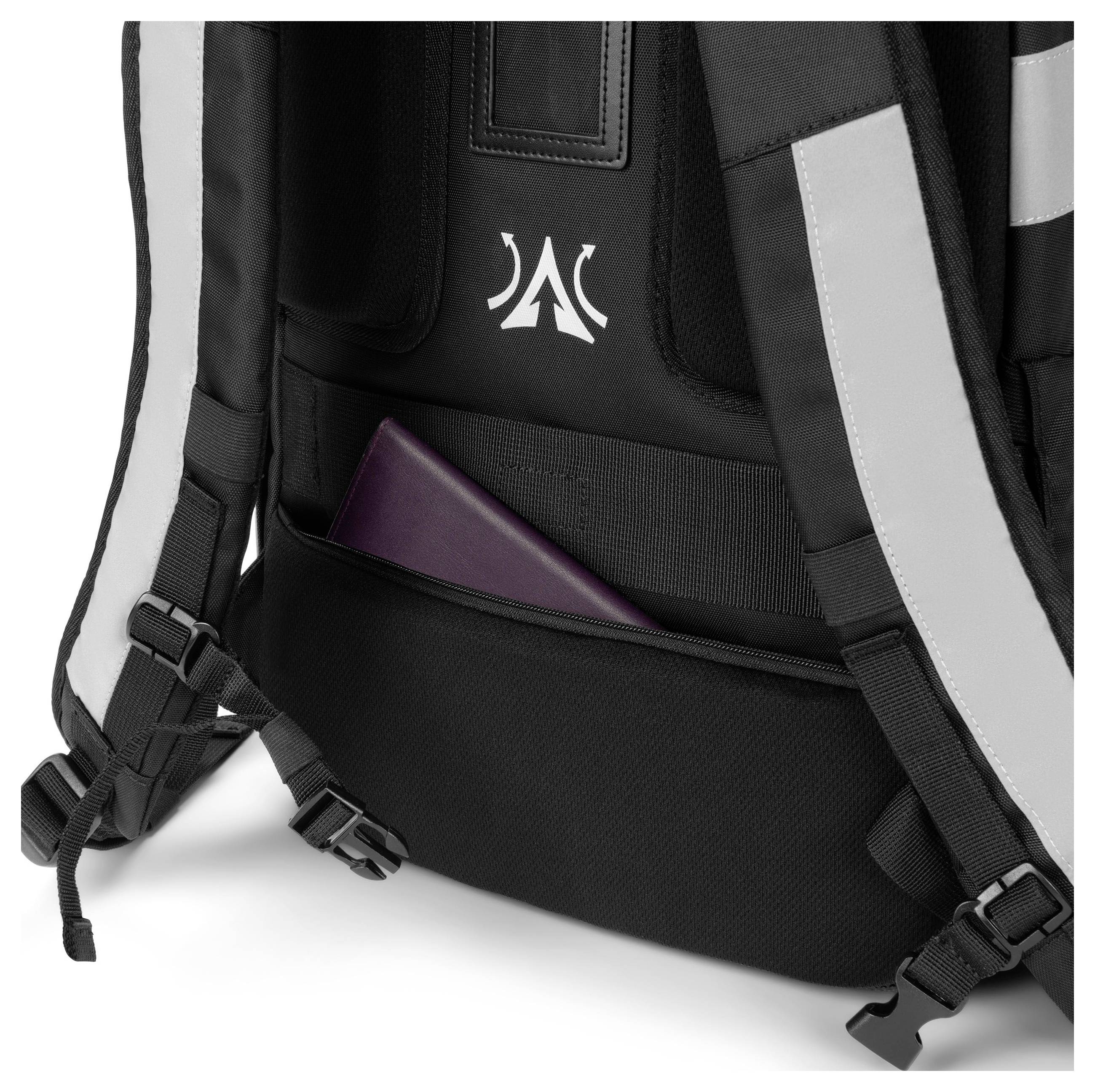 Ein schwarzer Rucksack mit grau-weißen Streifen zeigt ein Fach, in dem ein lilafarbenes Buch oder Notizbuch verstaut ist.