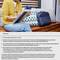 Eine Person sitzt draußen auf einem Holzboden mit einem Laptop und Notizbuch auf dem Schoß, umgeben von bunten Kissen.