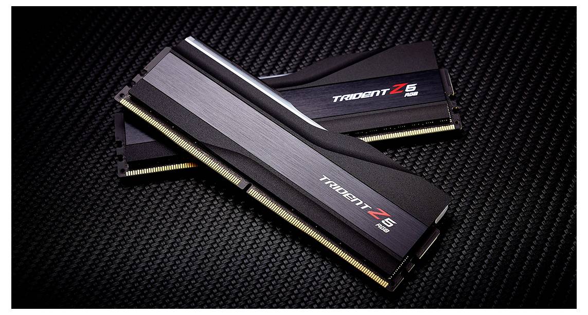 Zwei RAM-Module mit der Aufschrift 'Trident Z5'. Sie liegen diagonal auf einer schwarzen, texturierten Oberfläche.