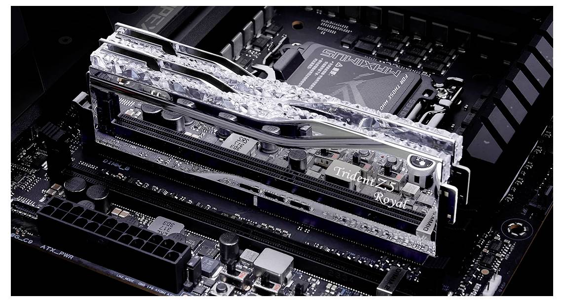 Nahaufnahme eines Computer-Motherboards mit dunkelgrauen Komponenten, zeigt eine glänzende silberne RAM-Einheit mit der Aufschrift 'Trident Z Royal'.