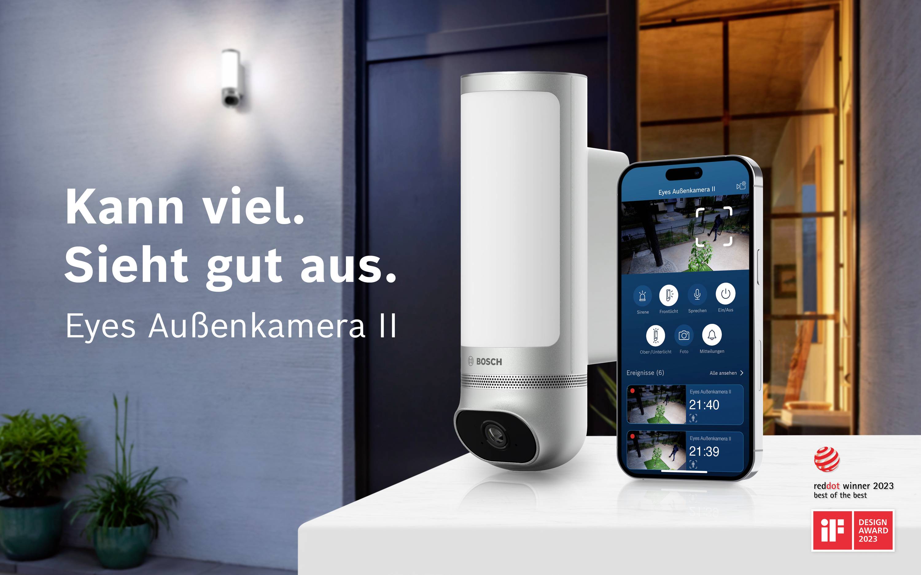 Weiße Sicherheitskamera von Bosch neben einem Smartphone, das Live-Überwachungsvideos anzeigt. Text: 'Kann viel. Sieht gut aus. Eyes Außenkamera II'.