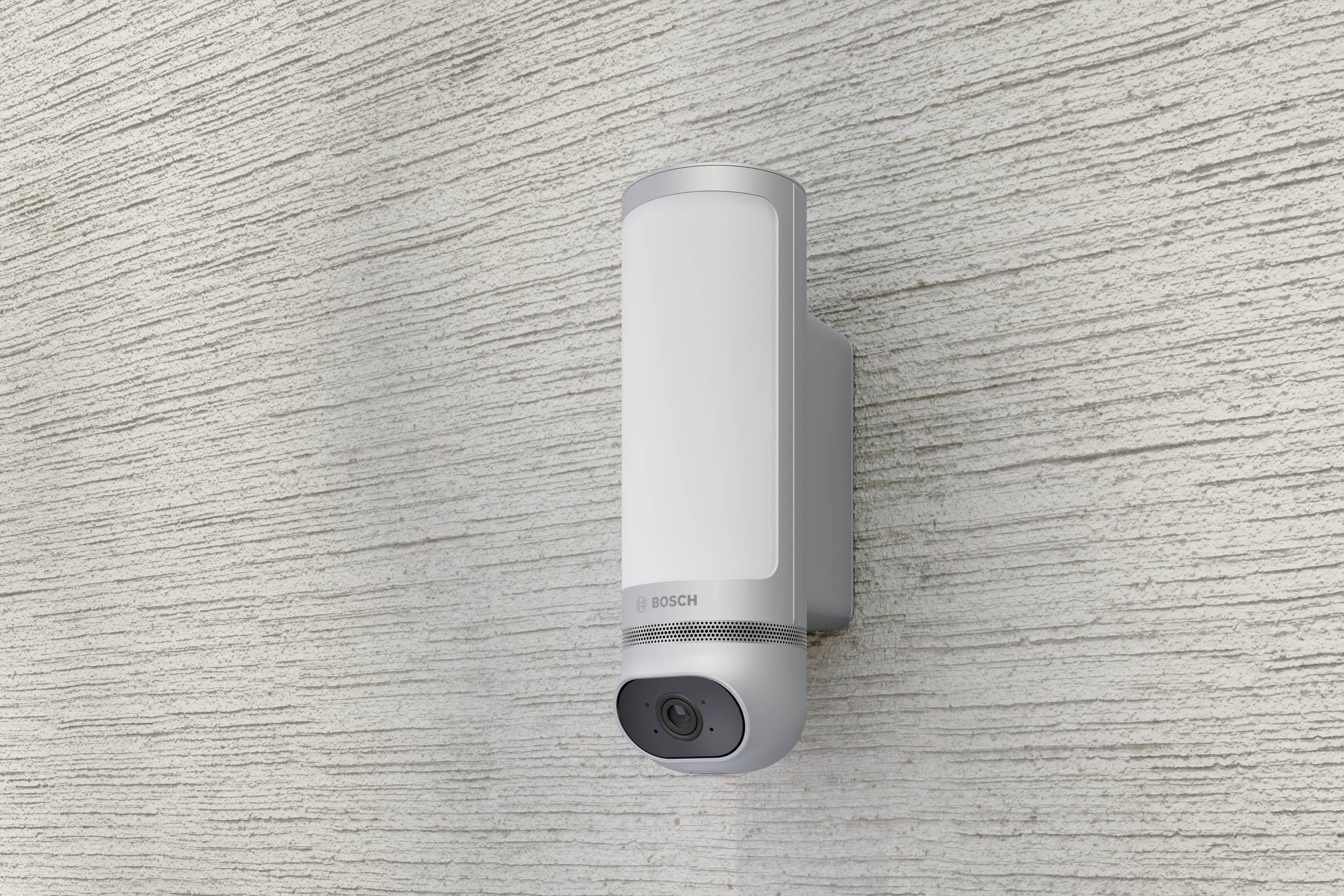 Außenkamera mit integriertem Licht, montiert an einer strukturierten Wand, bietet Sicherheit und Überwachung bei Tag und Nacht.