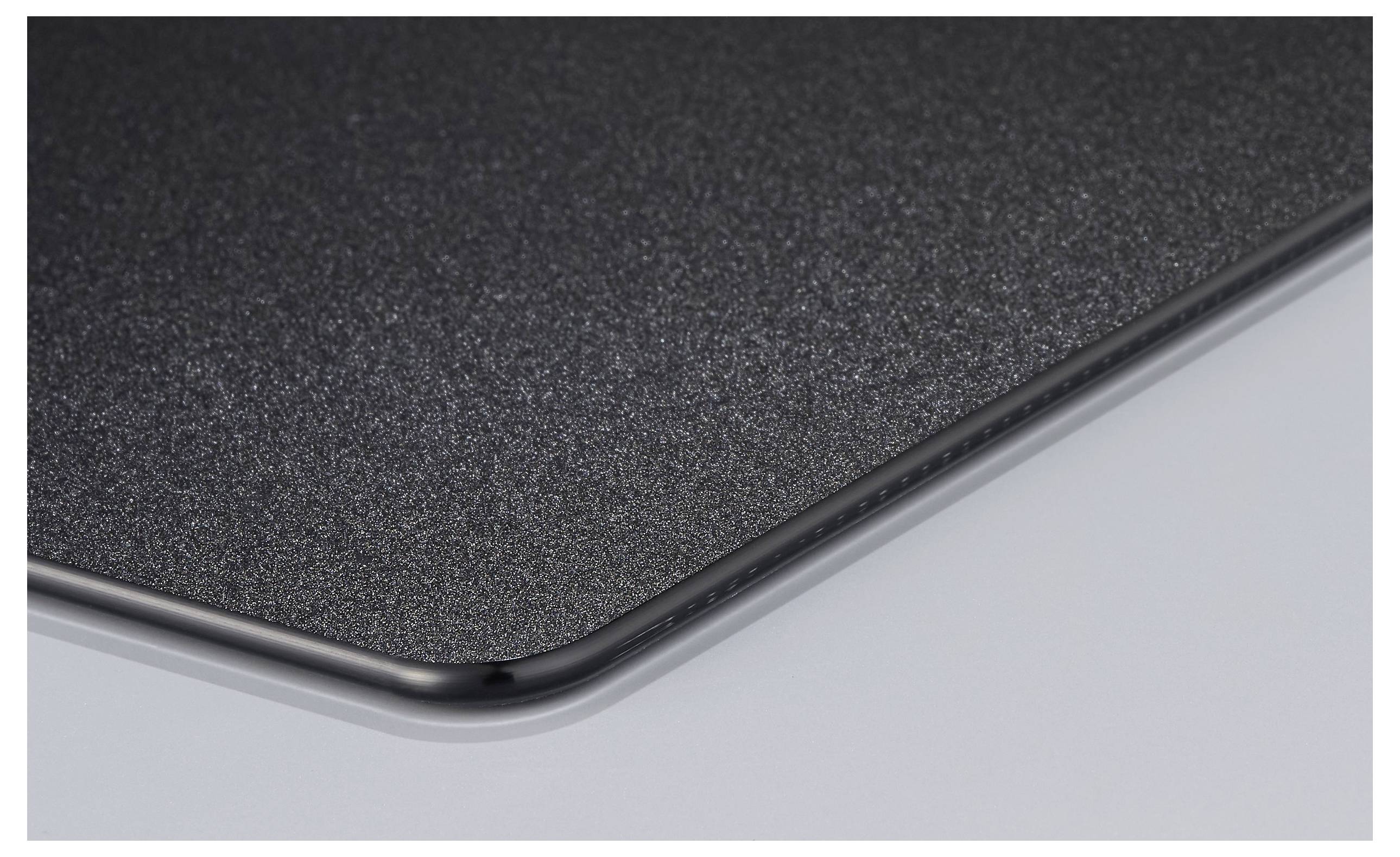 Die Ecke eines schwarzen Mauspads mit abgerundeten Kanten auf einer glatten Oberfläche.