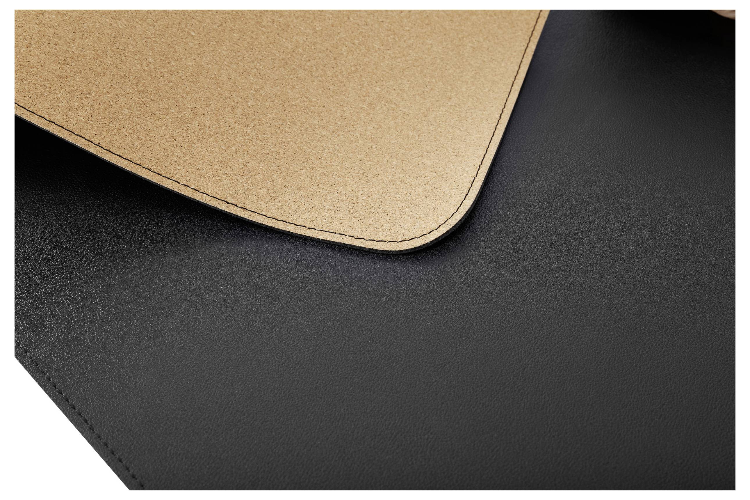 Nahaufnahme von zwei übereinanderliegenden Stoffen, oben helles Korkmaterial, unten schwarzes Leder, zeigt Kontrast der Texturen.