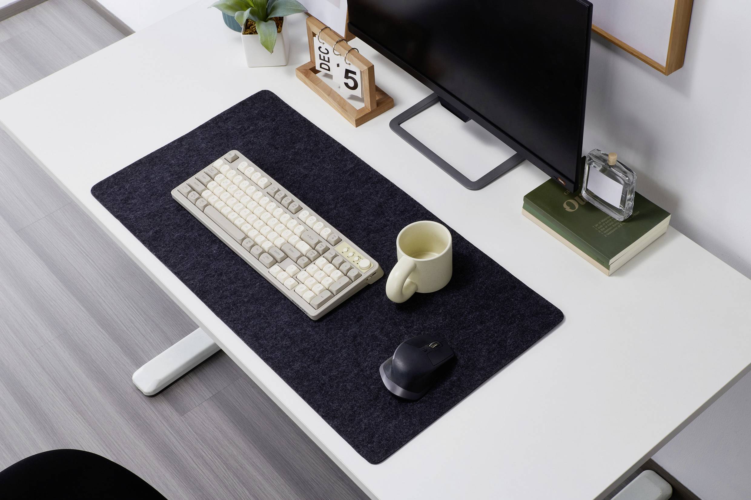 Eine Tastatur, Maus, Tasse und Monitor befinden sich auf einem Schreibtisch. Ein Kalender zeigt den 5. Dezember an.