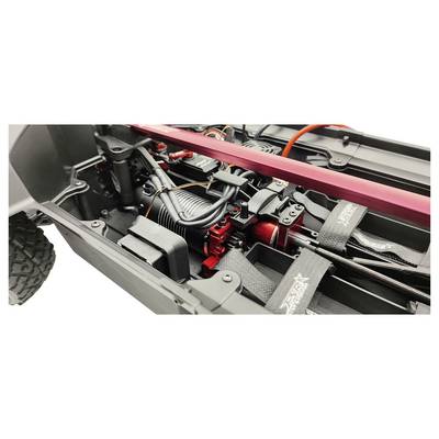 Nahaufnahme eines ferngesteuerten Autos mit Fokus auf dem Motor, Verkabelung und Federungselementen im Chassis. Dynamisches Design erkennbar.