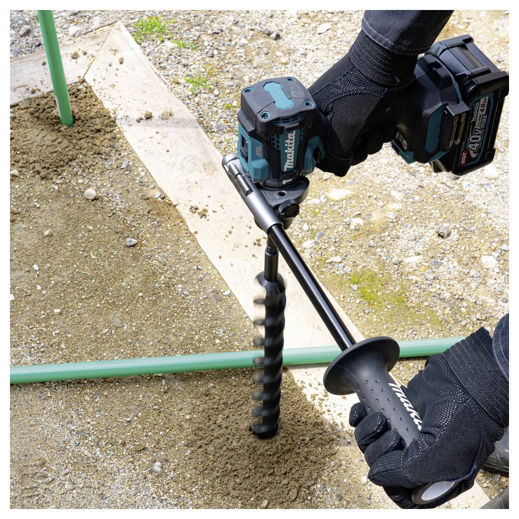 Handschuh tragender Arbeiter bohrt mit einem kabellosen Makita-Erdbohrer ein Loch in den Boden, wahrscheinlich für die Installation eines Zauns oder einer Pfosten.