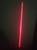Ein einzelner roter Laserstrahl, der vertikal durch eine dunkle Umgebung scheint.