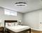 Helles Schlafzimmer mit modernem Deckenventilator und Doppelbett, umgeben von weißen Kissen und Holzmöbeln.