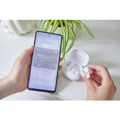'Person koppelt kabellose Kopfhörer mit einem Smartphone über Bluetooth. Kopfhörer sind in einem Ladecase, das Smartphone zeigt Verbindungsstatus.'