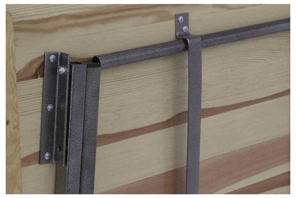 Metallschiene an einer Holzwand befestigt, mit Haken und Riemen. Dient zur sicheren Befestigung oder Aufhängung von Gegenständen.