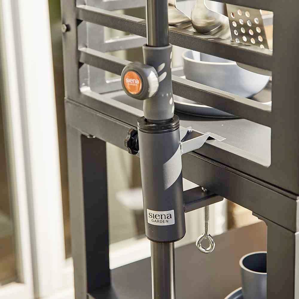 Metallischer Halter an einem Grillwagen, angebracht am Seitenständer mit dem Logo 'Siena Garden'. Teller und Küchenutensilien im Hintergrund.