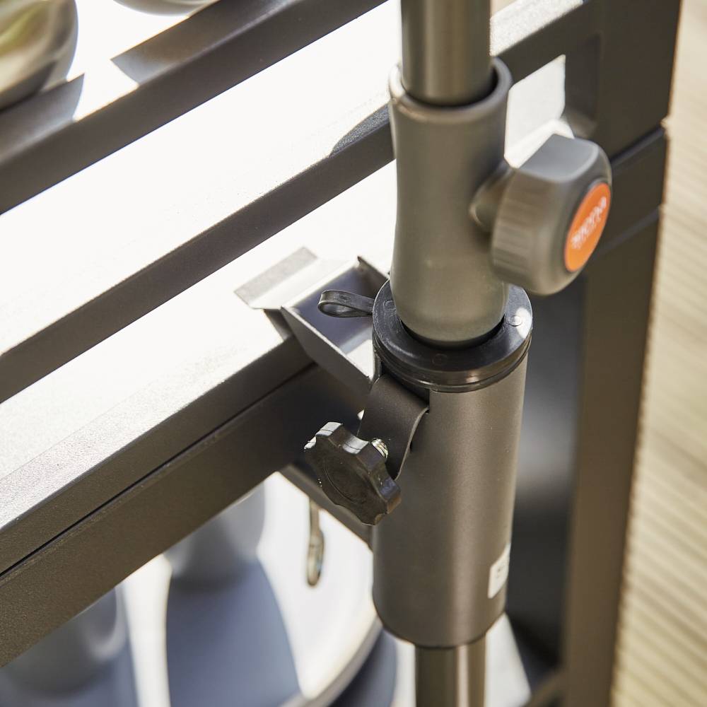 Ein schwarzer Schirmständer an einem Tisch befestigt, Nutzung für Sonnenschutz auf einem sonnigen Balkon erkennbar.