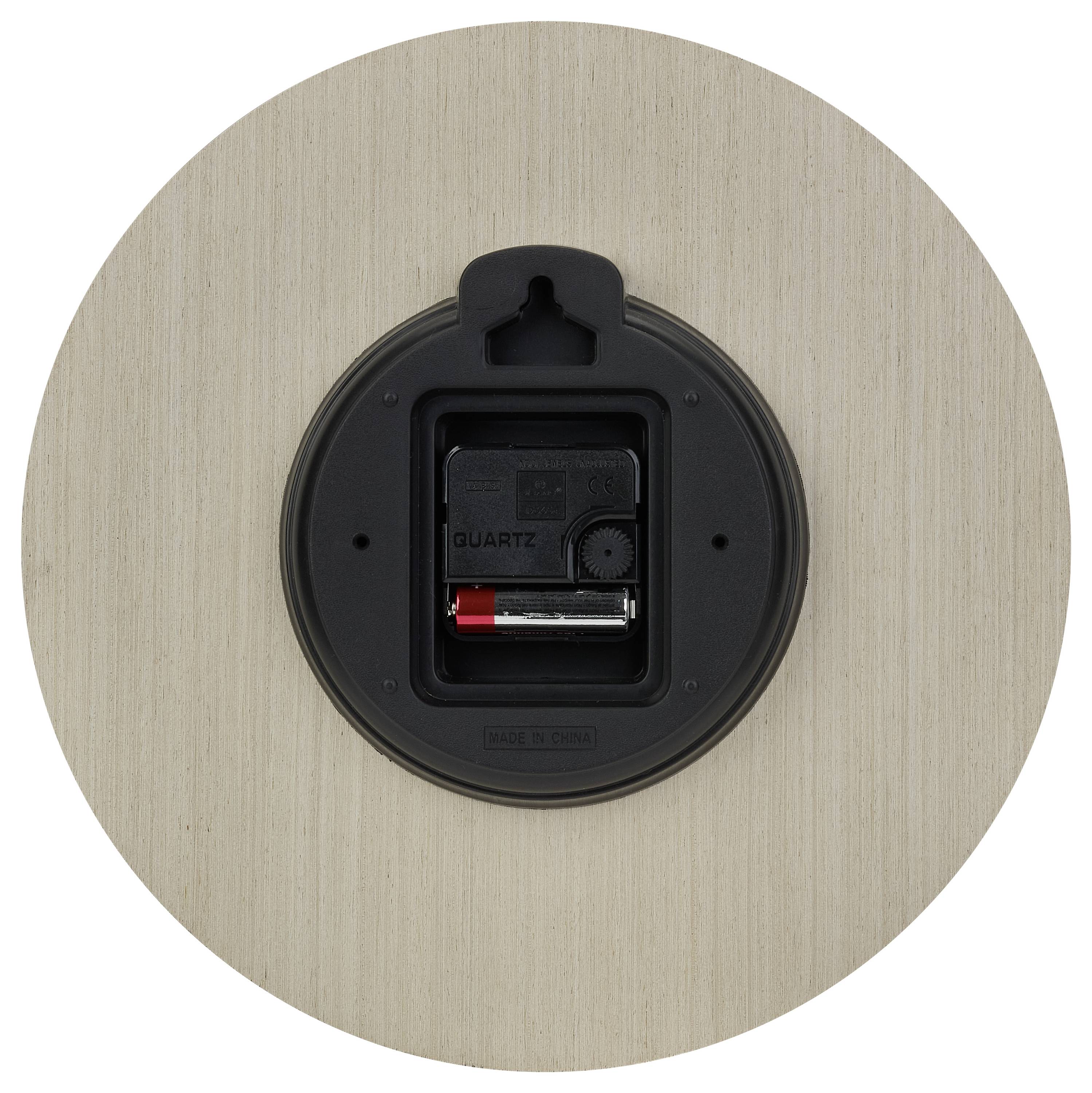 Rückseite einer runden Uhr mit Batteriefach und Mechanismus sichtbar. Holzähnliche Oberfläche.