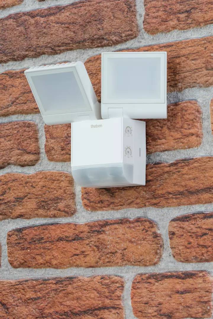 Bewegungsmelder mit zwei Flutlichtstrahlern an einer Ziegelwand montiert, bereit zur Erkennung von Bewegungen für Sicherheitszwecke.