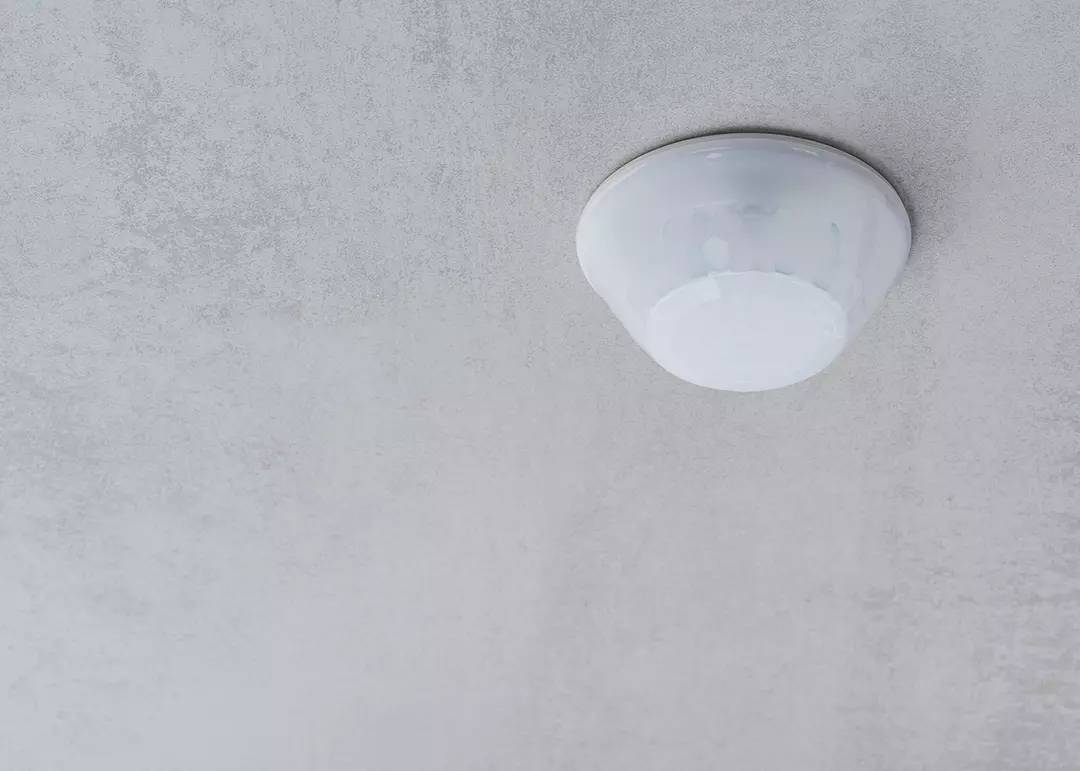 Eine runde, weiße Deckenleuchte an einer hellgrauen Decke.