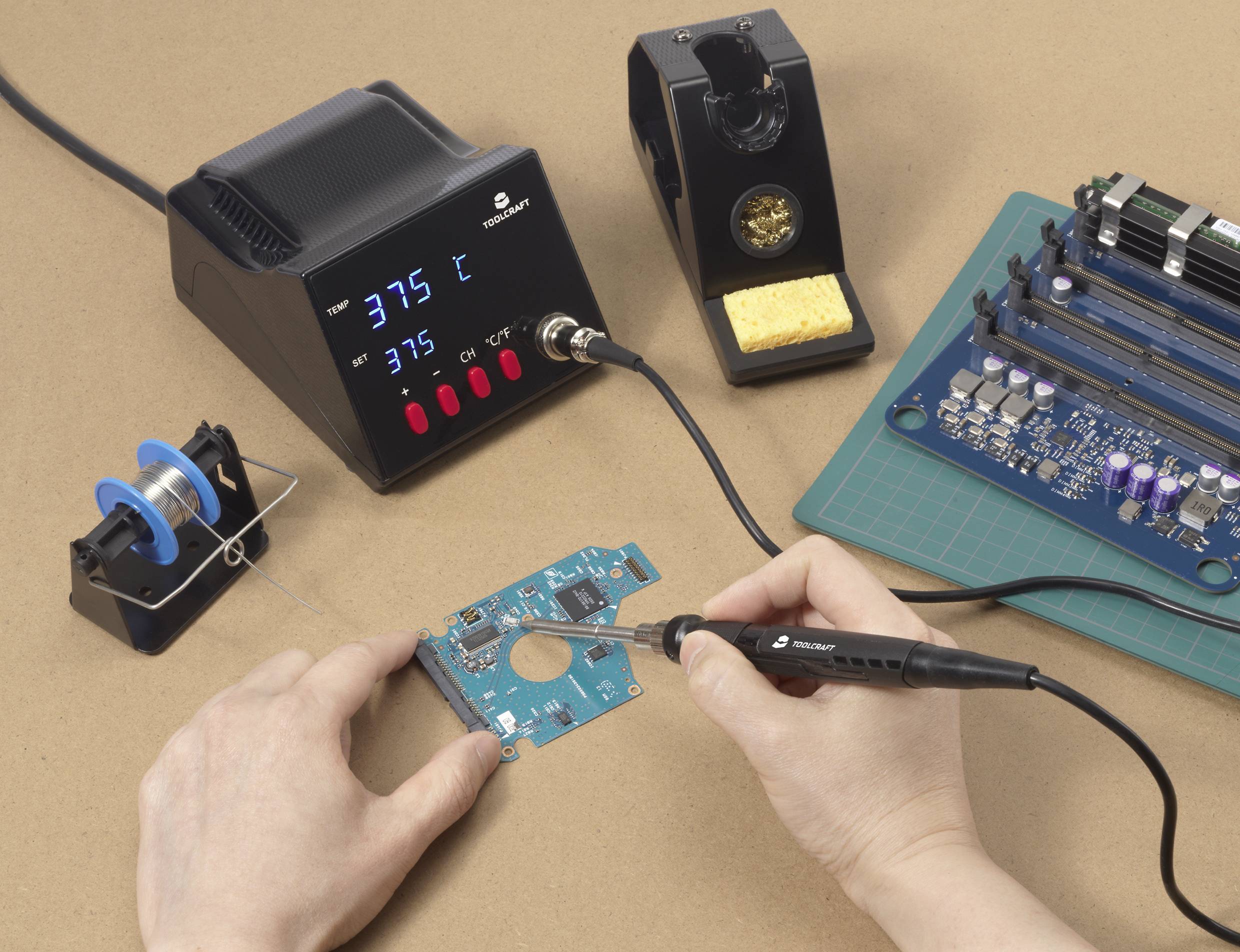 Ein Mensch arbeitet mit einem Lötkolben an einer blauen Leiterplatte, umgeben von einer Lötestation, Lötzinn und elektronischen Bauteilen.